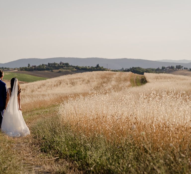 Bride & groom walk through gold fields in Tuscany on their wedding day 