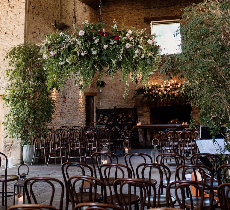 Cripps Barn wedding venue ceremony room with lots of greenery and colourful roses 