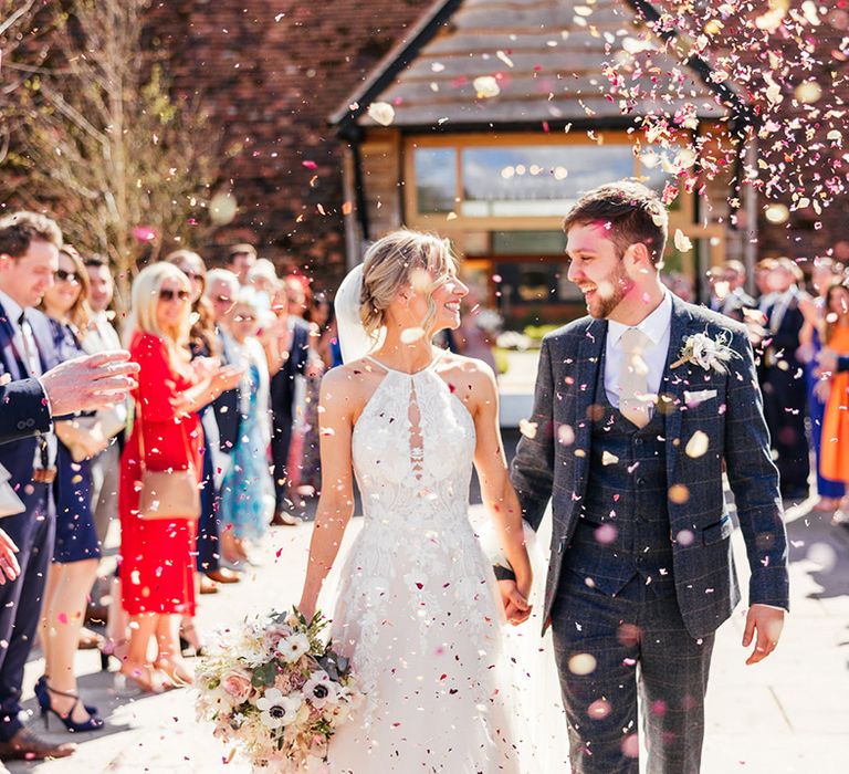 Bride and groom gaze at each other as they walk through colourful confetti together 