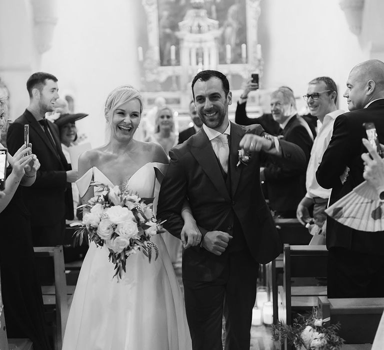 Bride & groom celebrate their marriage as they walk down the aisle after wedding ceremony 