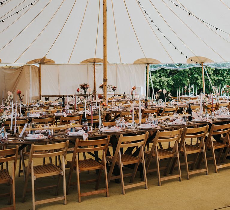 White marquee with festoon lighting with banquet tables and pink wedding decor 