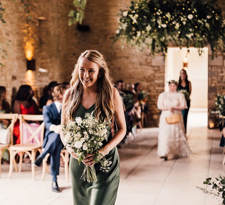 Bridesmaid in a green satin dress from Rewritten Bridesmaids with a white flower bouquet 