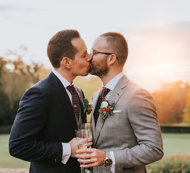 The two grooms share a kiss together during sunset golden hour 