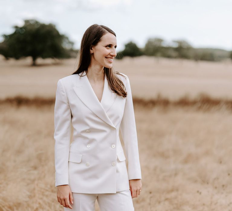 Bride in a double breasted white suit jacket and white suit trousers for the wedding 