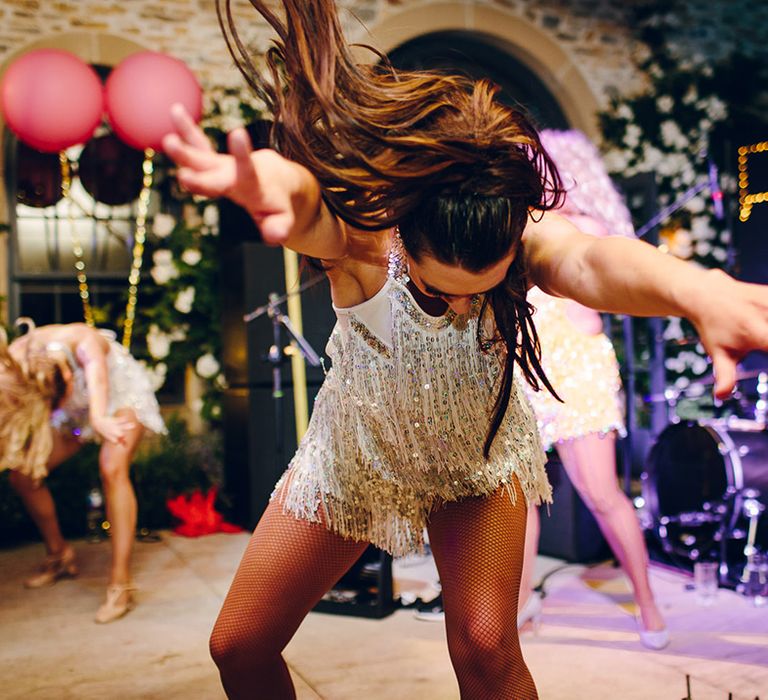 Dancer in white and silver sequin fringed party dress with halter neck and fishnet tights dancing on stage