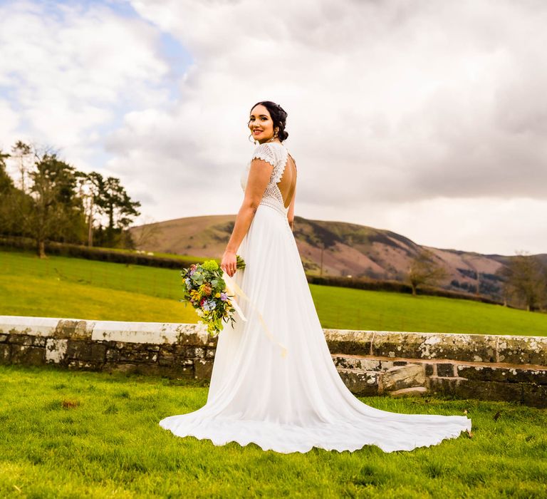 Bride wears lace open back wedding dress with puddle train 