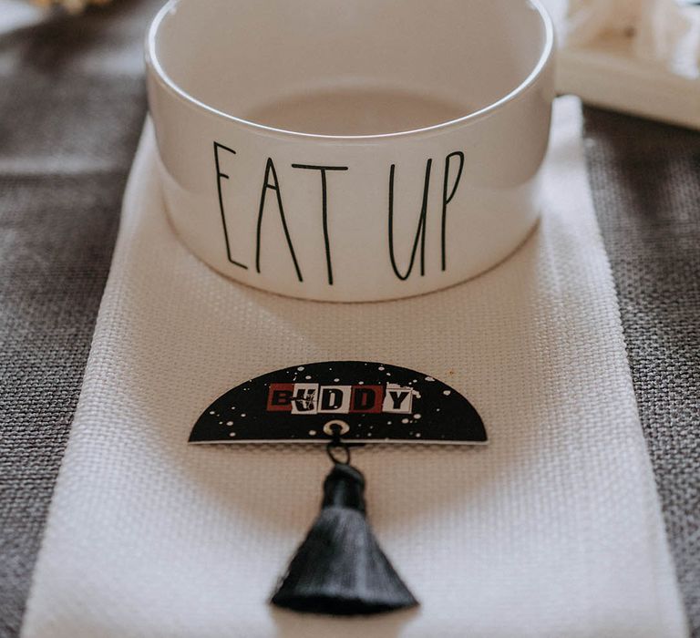 White bowl with "eat up" lettering and contemporary black, red and white wedding table name sign with black tassel 