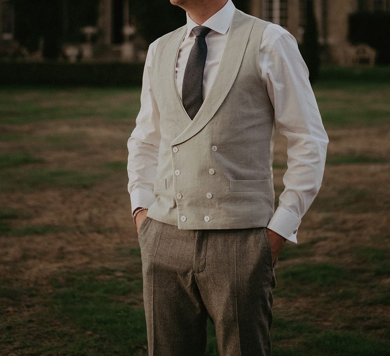 Groom wears white shirt and neutral waistcoat with dark tie 