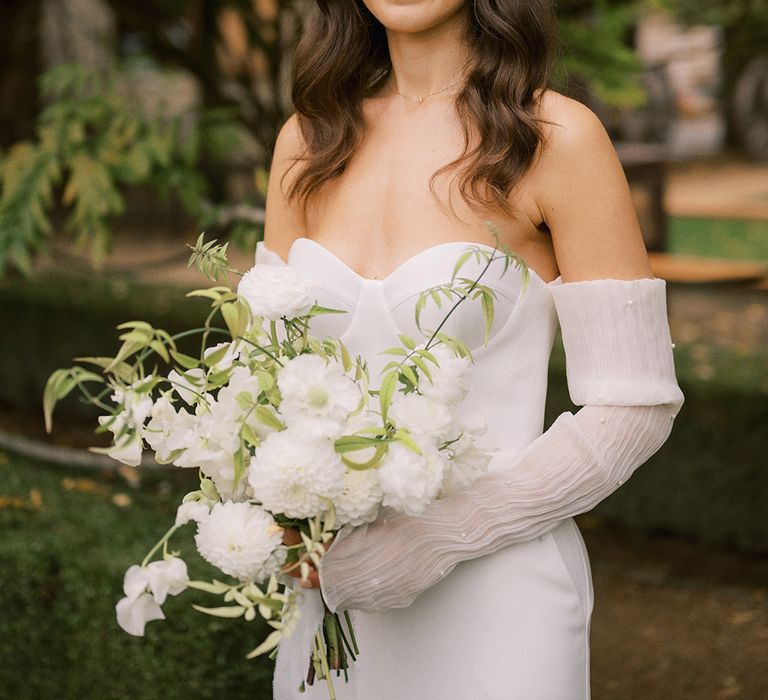 Corset style wedding dress from Bon Bride with detachable sleeves covered in pearls with white wedding flower bouquet 