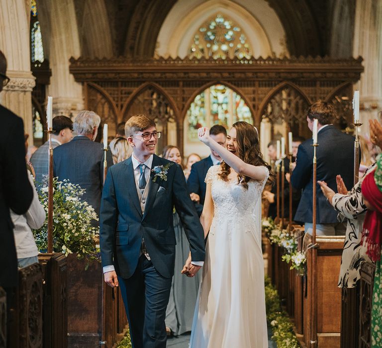 Bride and groom celebrate and smile brightly as they walk back down the aisle as a married couple