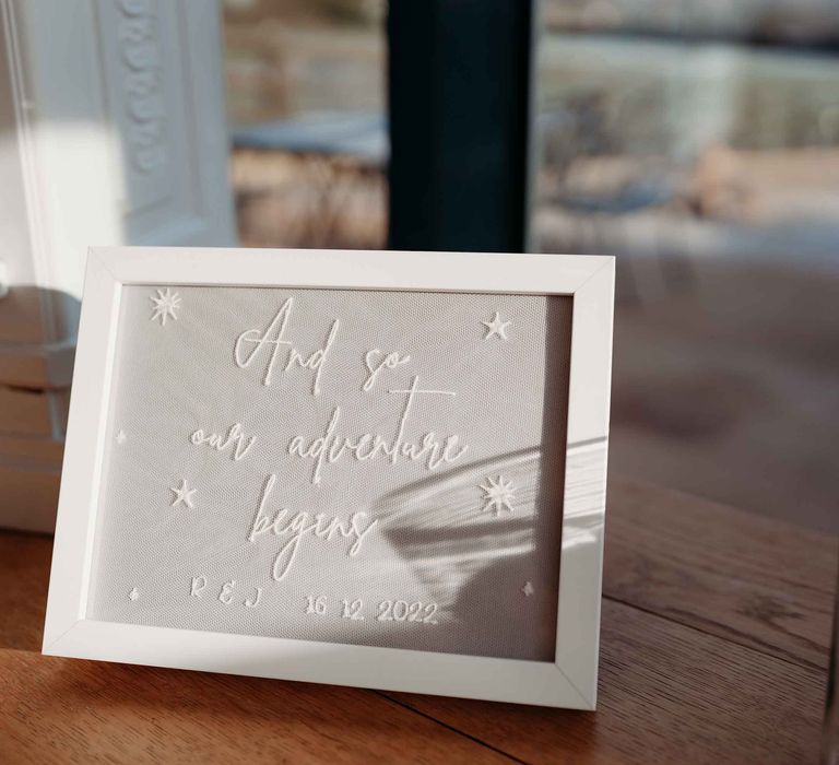 Embroidered wedding sign saying 'and so our adventure begins'