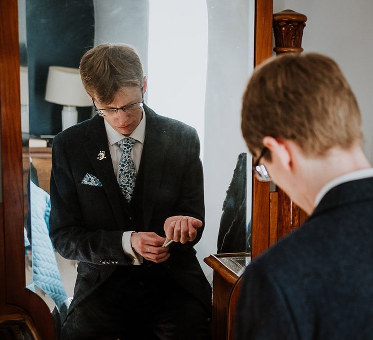 Groom puts on his cufflinks on the morning of the wedding day 