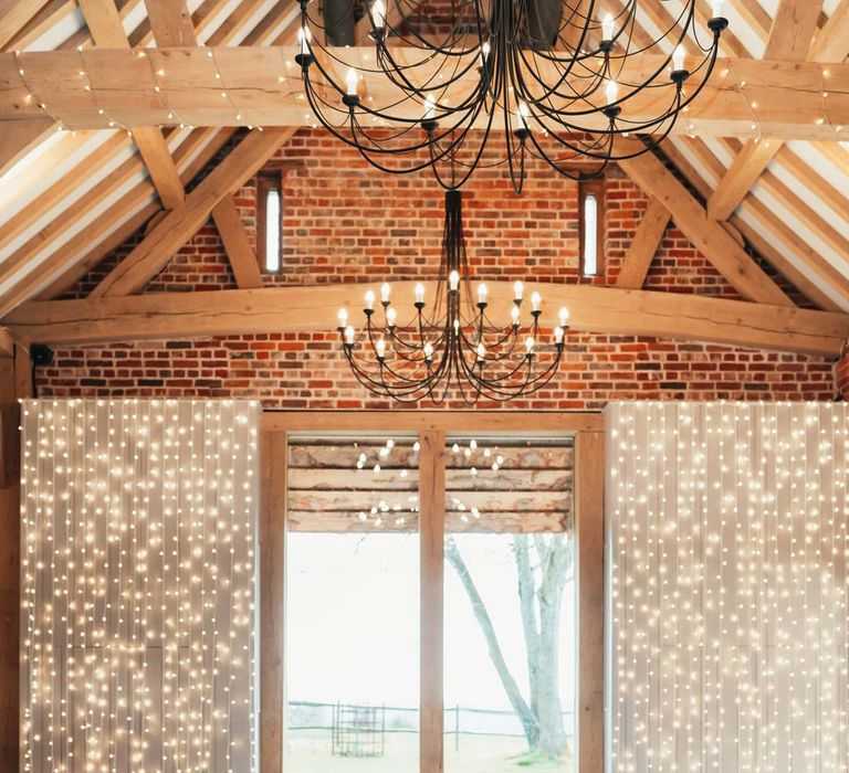 Peach and lilac spring-inspired wedding tablescape in Rackleys Barn reception room with wedding fairy lights wall and festoon chandeliers 