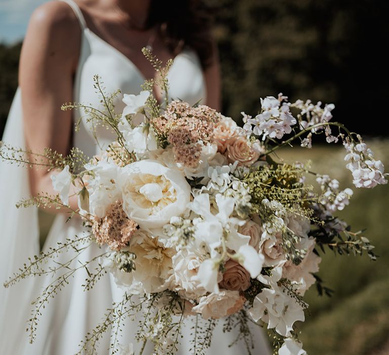 Bride holding a classic white and pale pink wedding bouquet with roses