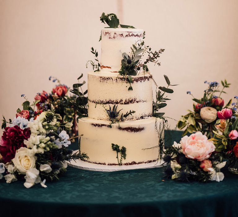 Three tier semi-naked rustic wedding cake decorated with white frosting 