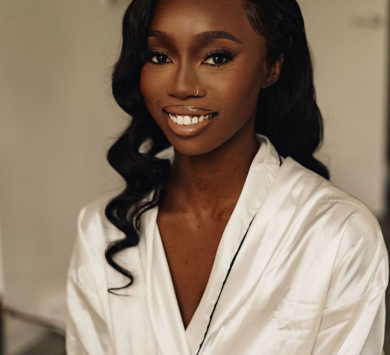 Nigerian bride wearing a white satin robe as she gets ready for the wedding 