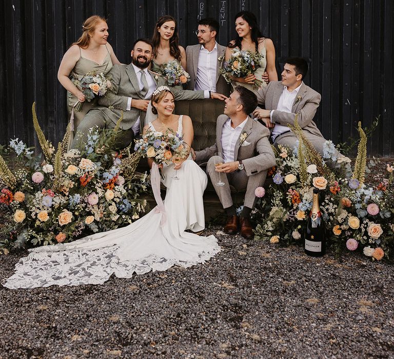 Rustic wedding venue with the bridesmaids and bride sitting on velvet green vintage sofa decorated with meadow flowers 