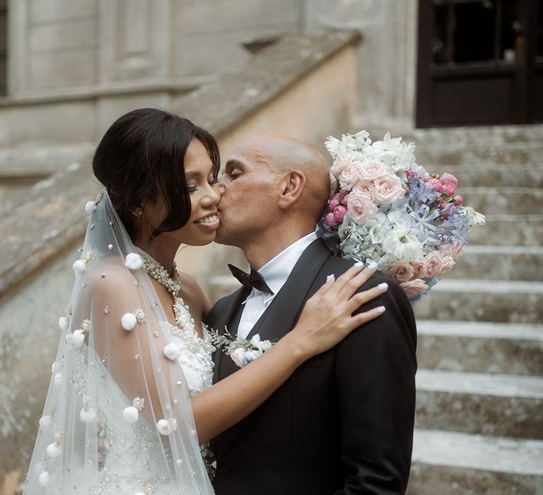 Pink, purple and white pastel wedding bouquet held by bride in sparkly wedding dress with the groom