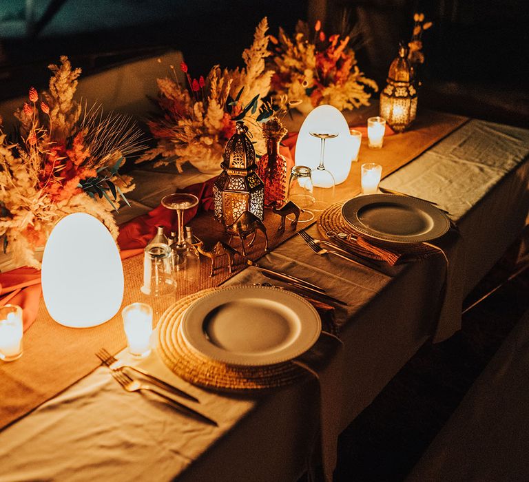 Romantic wedding tablescape with warm lighting and mini metal camels for boho destination wedding 