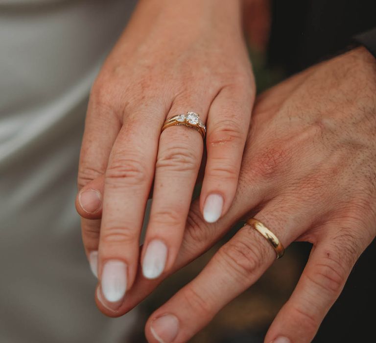 The bride and groom show off their gold and diamond wedding rings 