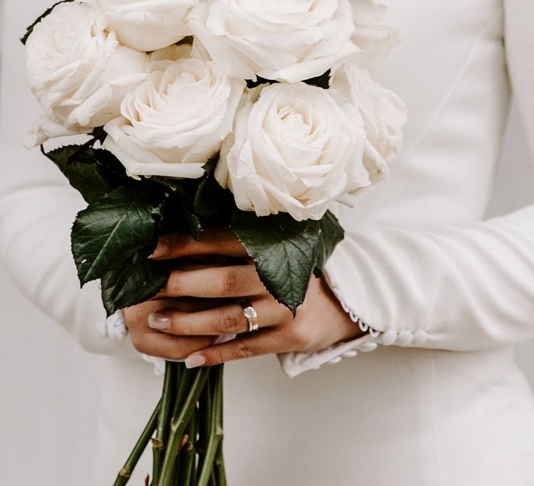 Bride holding all white bouquet of white roses 