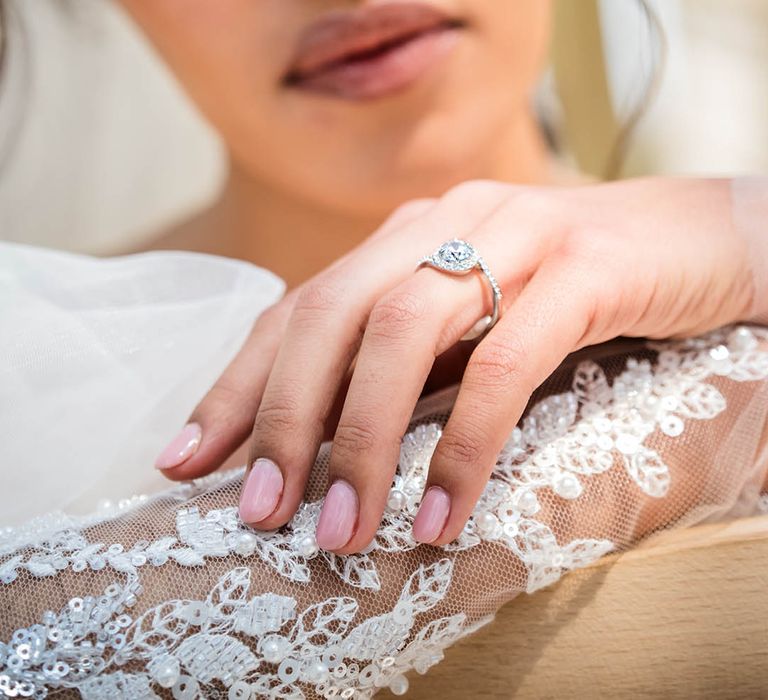 Bride wearing diamond engagement ring with lace long sleeve wedding dress