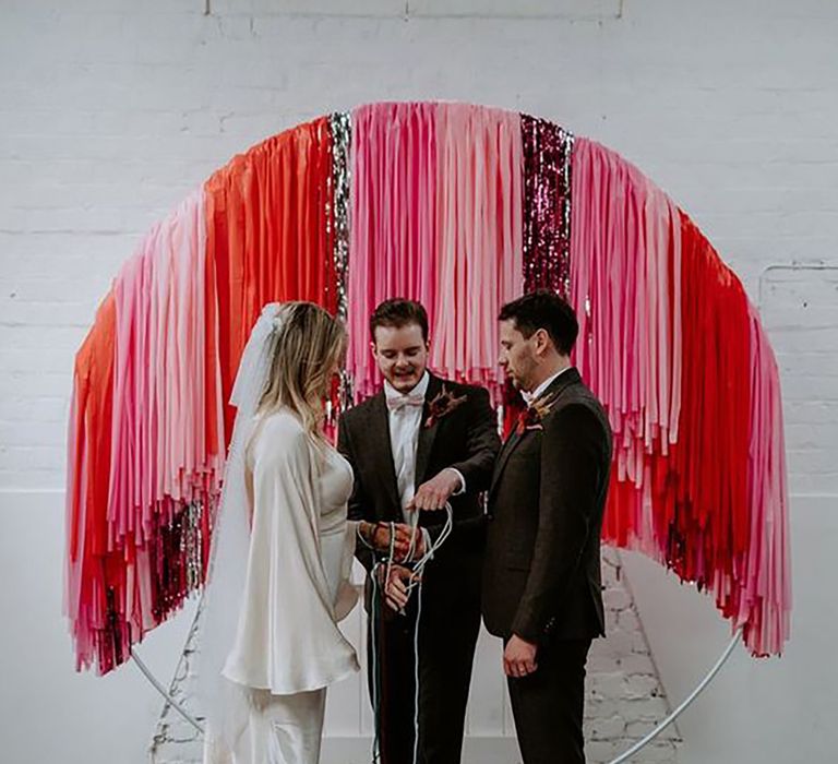 Couple at the alter partaking in handfasting ceremony on their wedding day