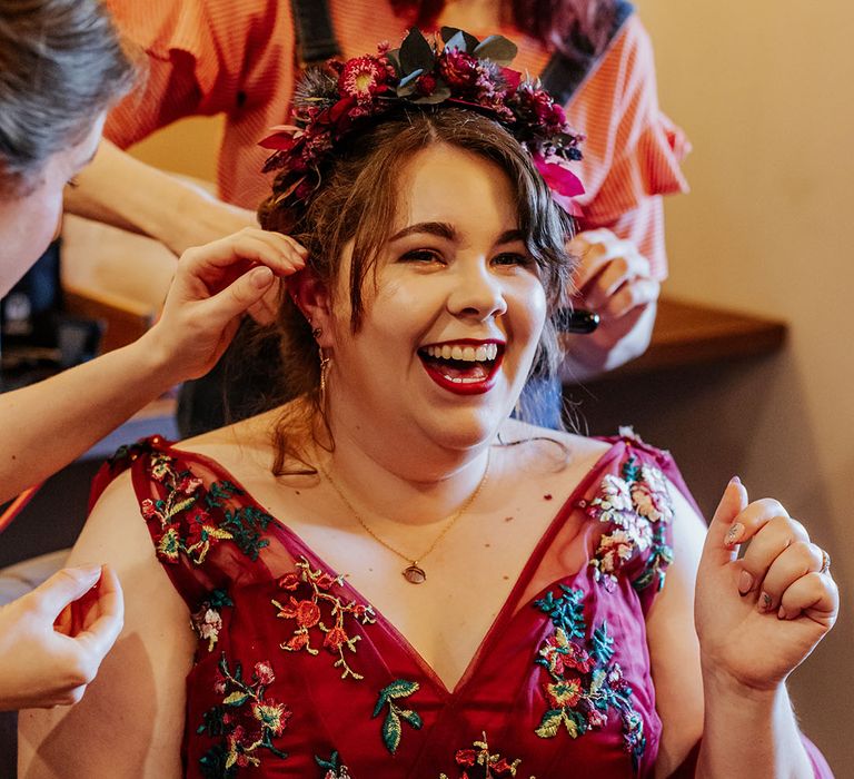 Bride in red embroidered wedding dress with flower crown hair accessory getting ready for the wedding 