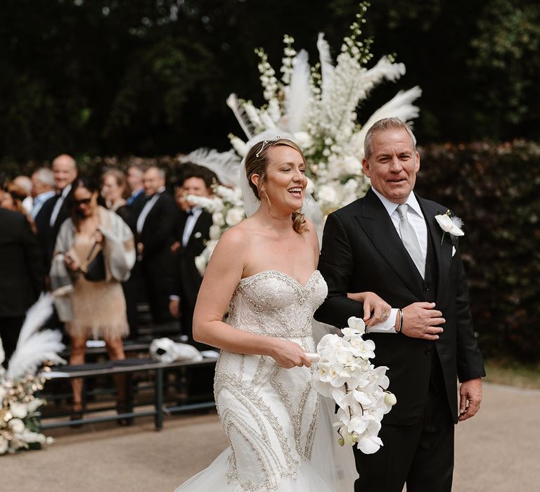 Bride in vintage inspired sweetheart mermaid wedding dress walking with the groom in a black suit after wedding ceremony 