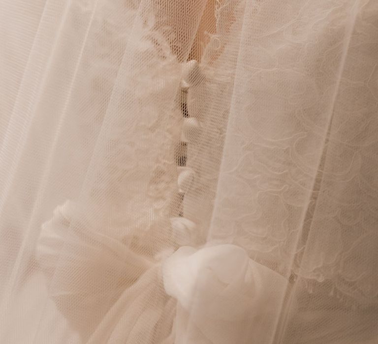 Bride wearing delicate lace wedding dress with bow detail 