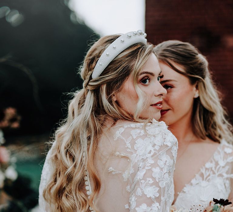 Bride in button back illusion wedding dress embracing bride at garden wedding 