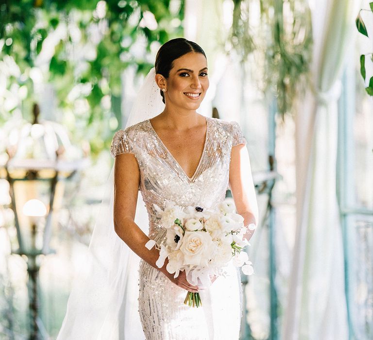 Bride in short sleeve sequin wedding dress carrying a white rose wedding bouquet for classic wedding at castle venue 