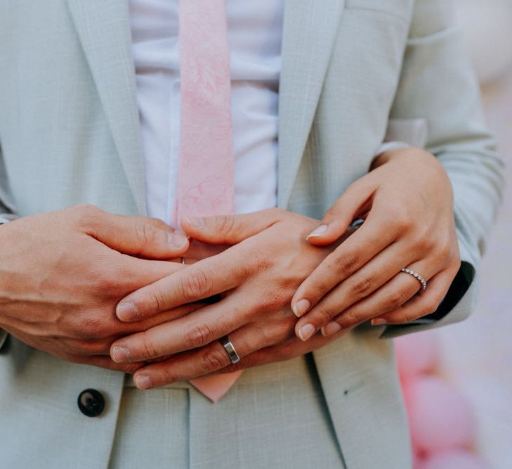 Bride and groom embracing and showing off wedding jewellery 