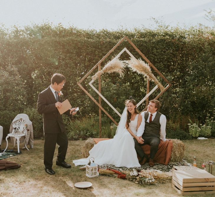 wedding reception at home with bride and groom sitting on a hay bale 