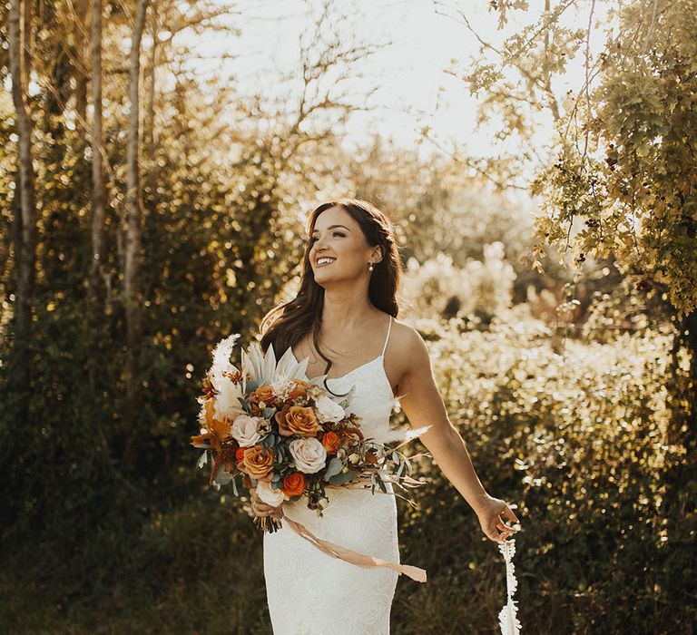 Bride holds autumnal wedding bouquet for wedding portrait session