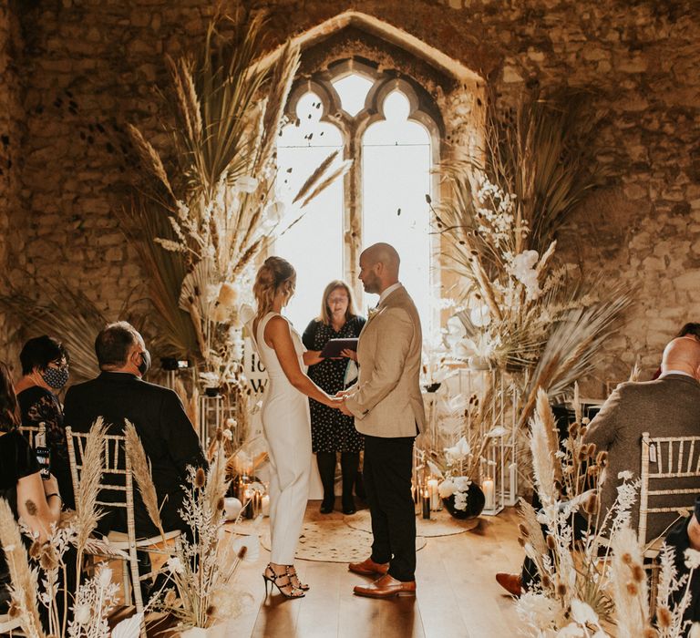 Bride and groom exchanging vows at intimate wedding with dried flowers wedding decor 