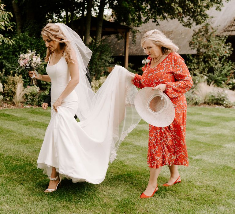 Mother of the bride holding her daughter wedding dress train 