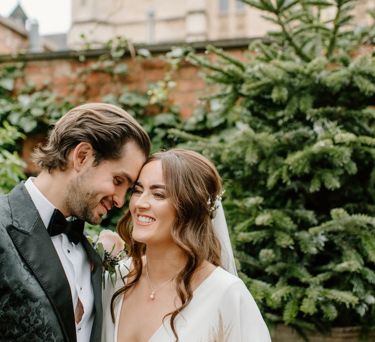 Bride and groom smiling with Christmas tree in the background for December wedding