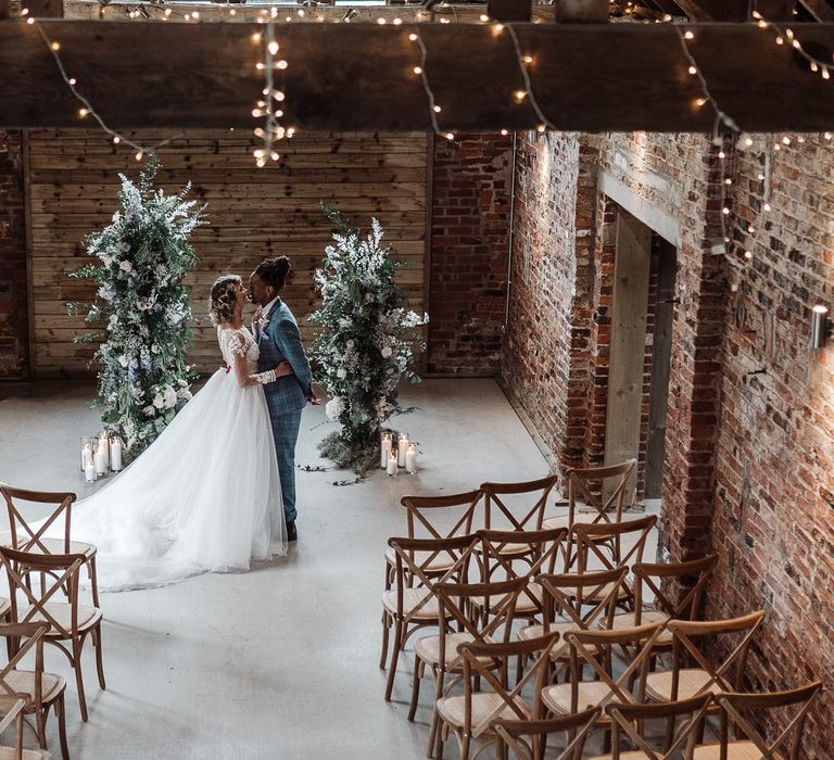 Fairy lights, exposed brick and large flower plinths for a romantic barn wedding