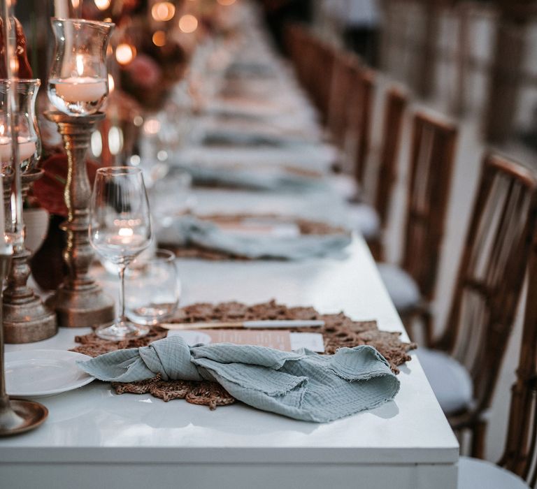 Place setting with natural wicker place mat, blue linen napkin and pink menu card for destination wedding 