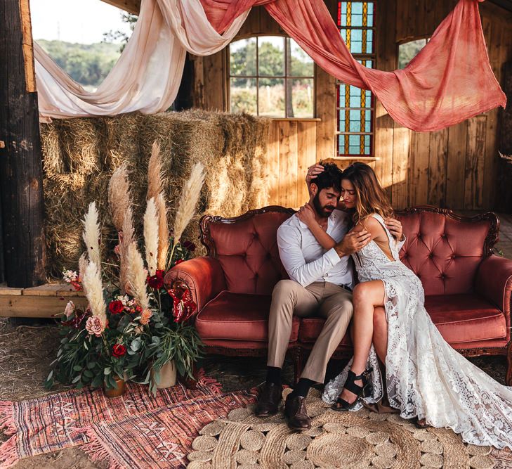 Bride & groom sit together on chic pink sofa