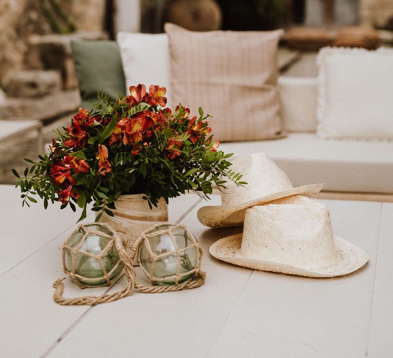 Two white wicker hats next to colourful floral bouquet on table