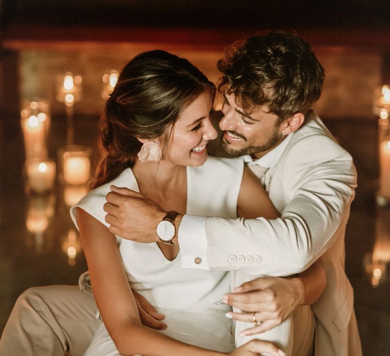 Groom in a beige suit embracing his boho bride in separates 