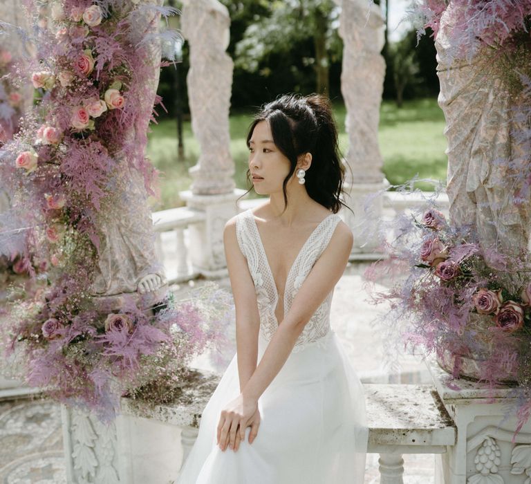 Bride looks ahead wearing low cut lace gown 