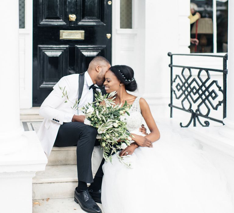 Bride & groom kiss on doorstep in London with black door in the background