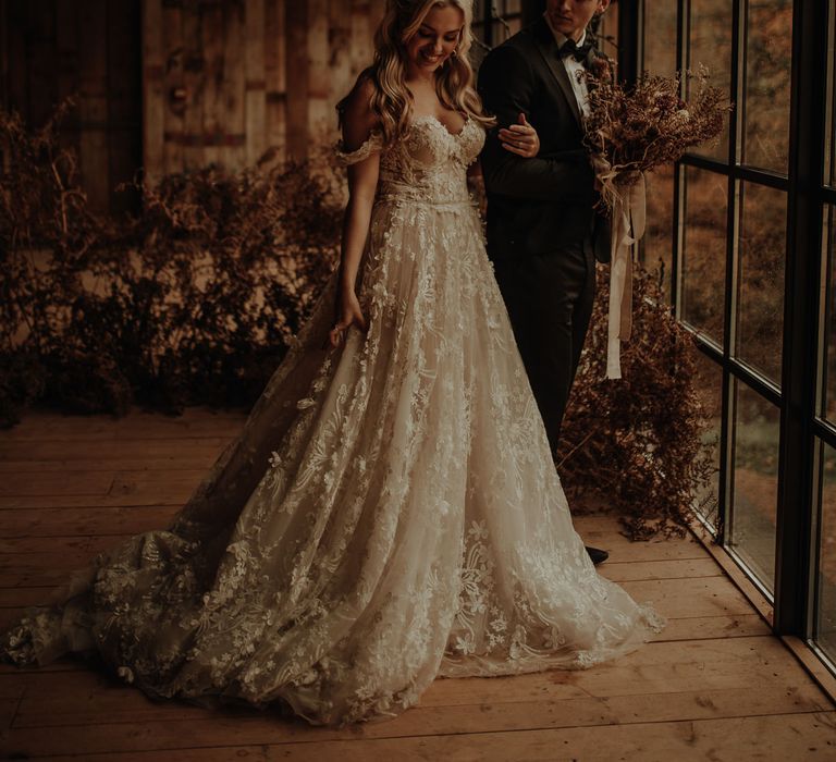 Bride with long wavy hair wearing a lace wedding dress with full skirt and fitted bodice. 