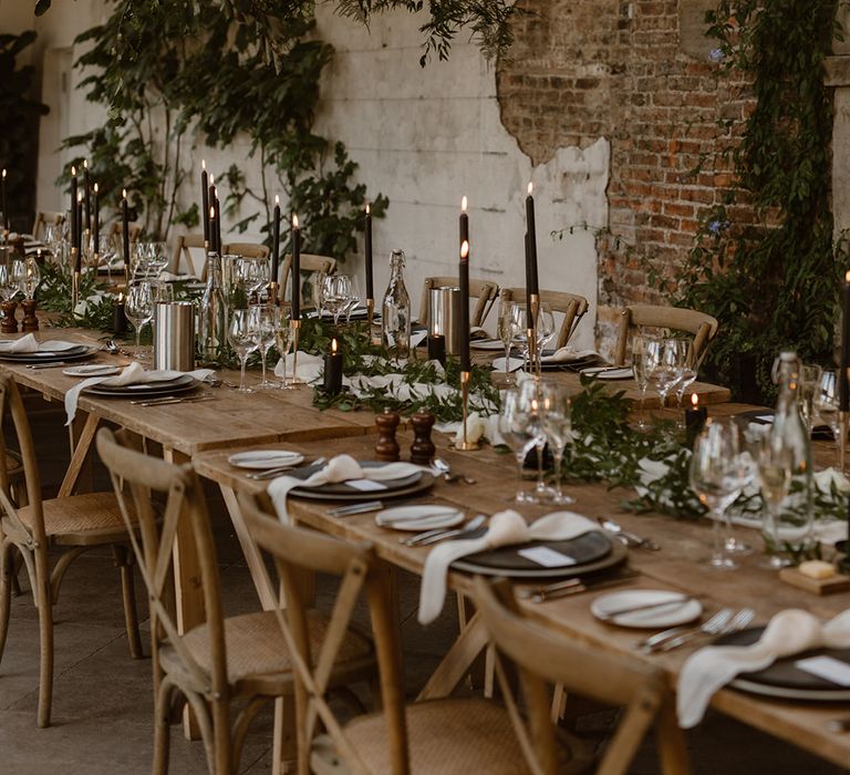 Wooden wedding table with rustic decor, wooden chairs, foliage cloud, greenery and black candles in the Fig House at Middleton Lodge