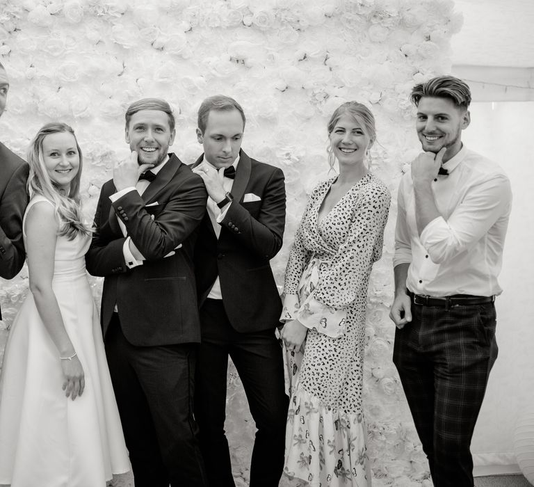 Wedding party pose in front of flower wall in black & white image