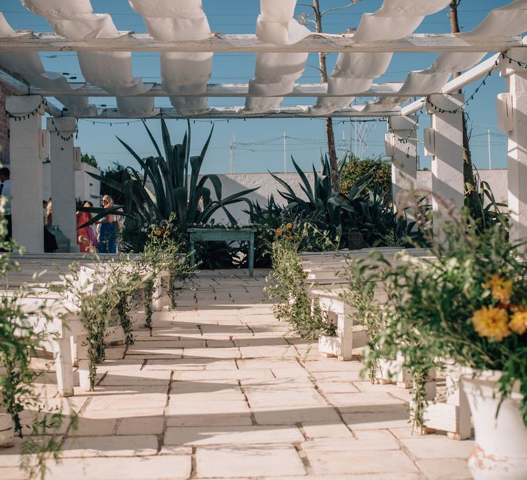 Rustic outdoor wedding ceremony at Masseria Potenti with olive leaf foliage and orange flowers