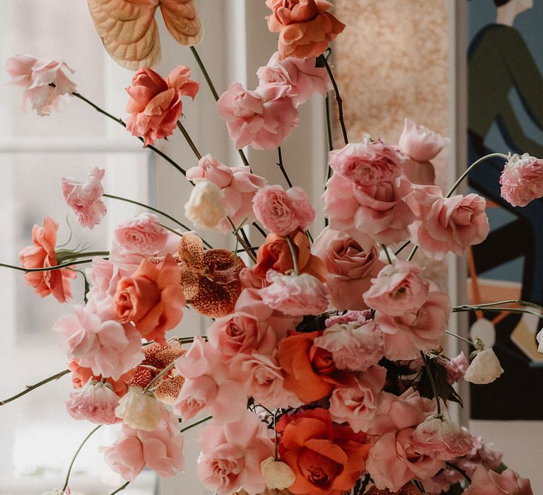 Pink and peach wedding flower display with  ranunculi, garden roses and orchids